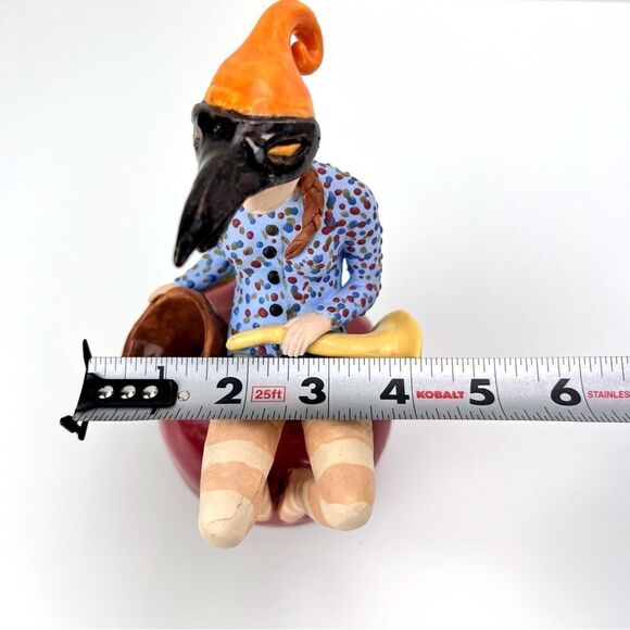 CARRIANNE L HENDRICKSON woman with beak hat sitting on apple sculpture 2… - Picture 16 of 16